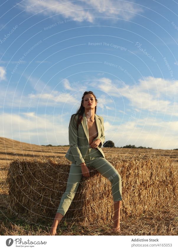 Modische junge Frau ruht auf Heuhaufen in der Landschaft ruhen Heugarben selbstbewusst Stil Mode sinnlich nackt Natur Model ruhig schlank Anzug Barfuß Körper