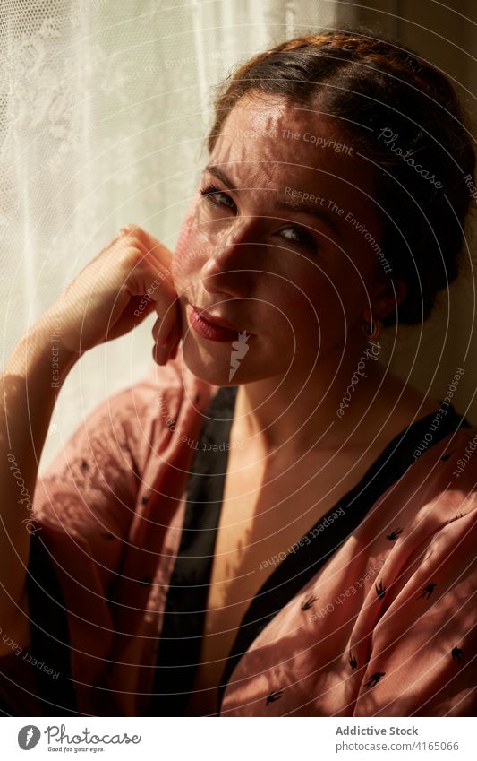 Nachdenkliche junge Frau entspannt sich am Fenster zu Hause ruhen verträumt besinnlich Hand auf die Wange sich[Akk] entspannen Stil feminin Vorschein