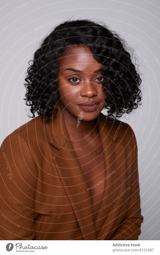 Charmante schwarze Frau im Studio Jacke lässig selbstbewusst Model Stil Atelier Teint charmant Vorschein ethnisch Afroamerikaner trendy Windstille krause Haare
