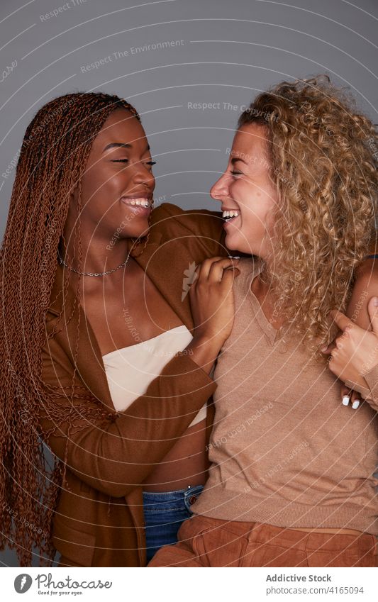 Fröhliche multiethnische Frauen lachen im Studio Lachen Freundschaft Spaß haben Witz Humor kuscheln bester Freund Atelier vielfältig rassenübergreifend schwarz