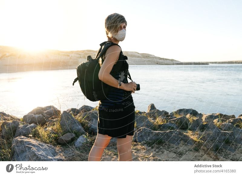 Anonyme Dame bewundert Meerblick von der Felsenküste bei Sonnenuntergang Frau Meeresufer Reisender bewundern Erholung Urlaub neue Normale Ausflug MEER Feiertag