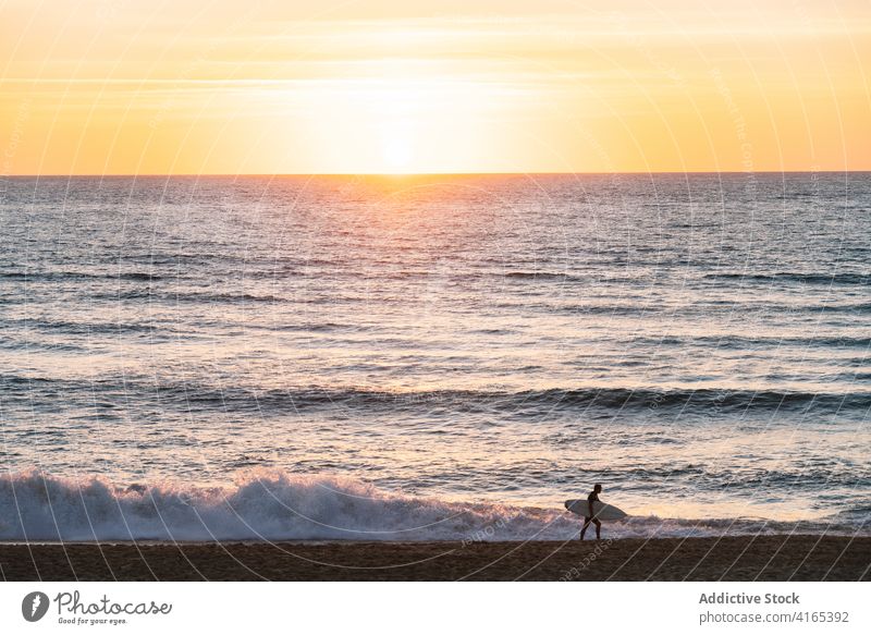Silhouette eines Surfers, der bei Sonnenuntergang am Strand spazieren geht Person Spaziergang Meer Surfbrett winken Himmel Urlaub Natur Wasser Aktivität extrem