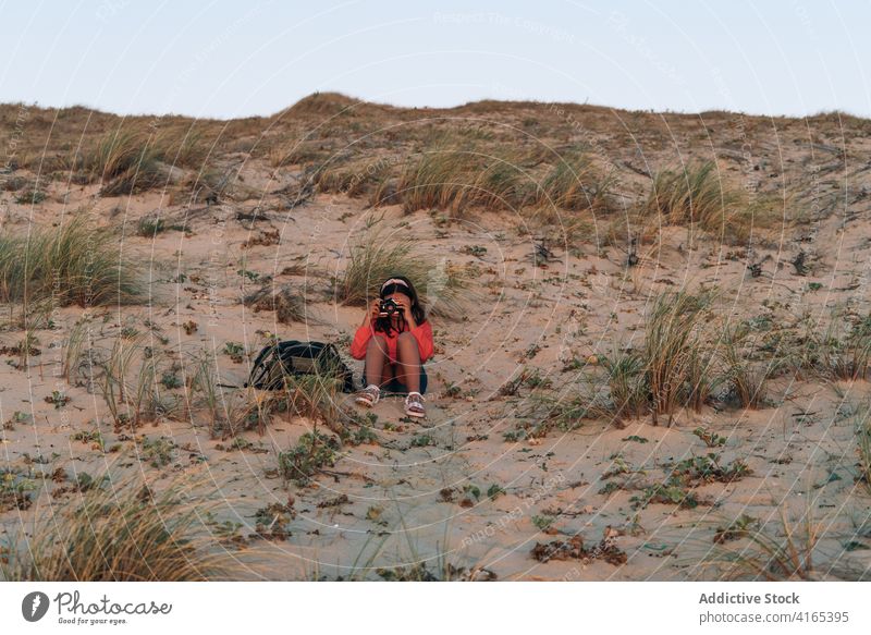 Teenager-Mädchen, das Fotos mit der Kamera am Sandstrand macht fotografieren Strand Düne Natur reisen Erholung Fernweh genießen bewundern jung Stil Sommer