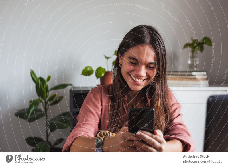 Aufgeregte junge Frau, die zu Hause auf ihrem modernen Smartphone surft Browsen aufgeregt Zahnfarbenes Lächeln Freude Surfen Telefon Mobile Gerät Internet