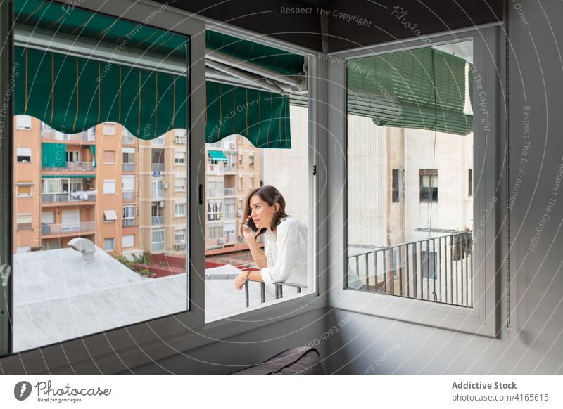 Junge Frau spricht auf dem Balkon mit ihrem Smartphone reden Gespräch Telefonanruf Kommunizieren diskutieren heimwärts sich[Akk] entspannen Anschluss Mobile