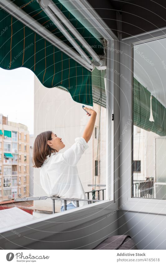 Junge Frau macht Selfie mit Smartphone auf dem Balkon heimwärts sich[Akk] entspannen Foto Anschluss Mobile Telefon jung Bild lässig brünett Reling tagsüber