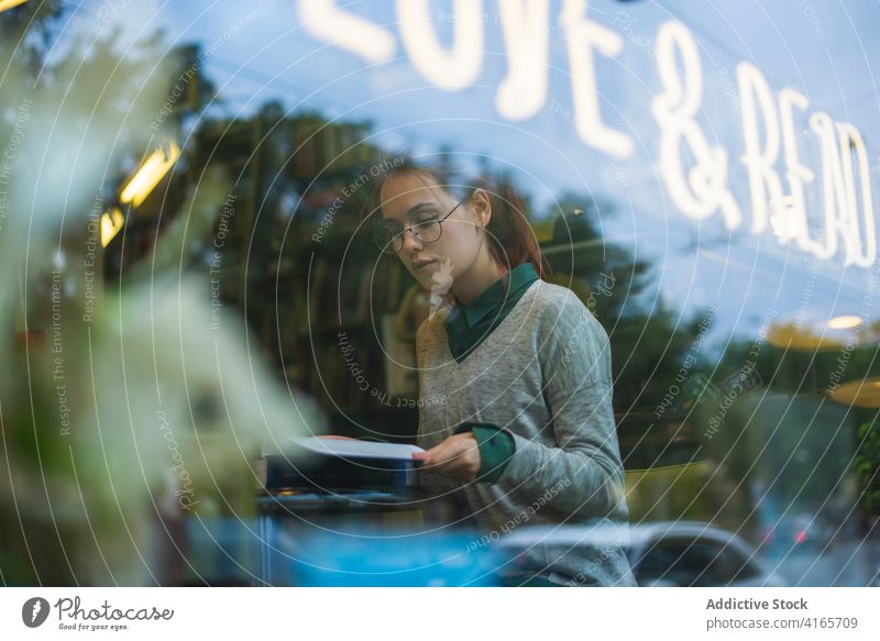 Ruhige Frau mit Buch in gemütlichem Cafe nachdenklich Café Wochenende sich[Akk] entspannen klug genießen Stil warm Tasse Literatur Fenster Tisch lässig Getränk