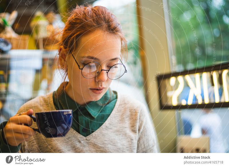 Junge Frau genießt heißen Kaffee in einem Café trinken Stil tausendjährig genießen Heißgetränk Aroma gemütlich aromatisch Getränk Wochenende sitzen