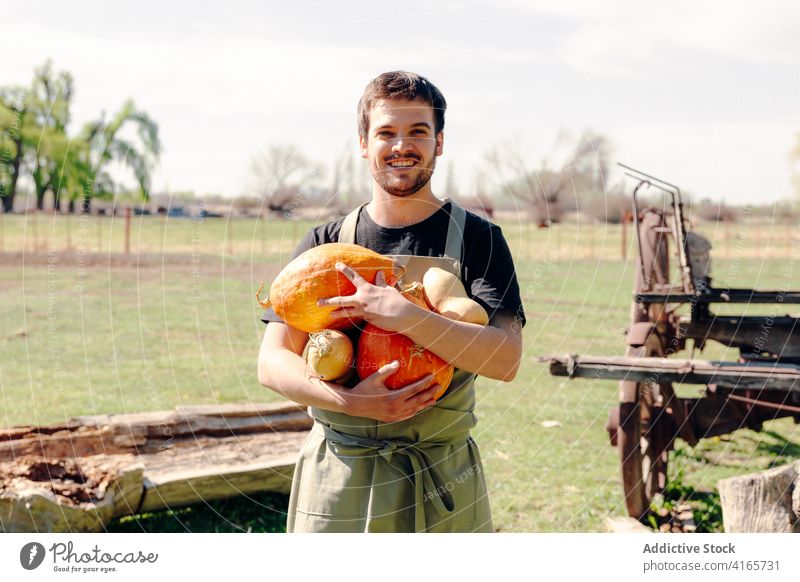 Lächelnder Bauer mit Kürbissen auf dem Lande Ernte Landwirt Mann Freude Squash Gemüse Landschaft Dorf Saison männlich orange positiv Optimist heiter Glück