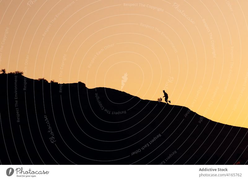 Anonyme Person, die bei Sonnenuntergang auf einem Hügel läuft laufen Berge u. Gebirge Berghang Training Athlet Aufstieg Silhouette Übung Gesundheit Sport