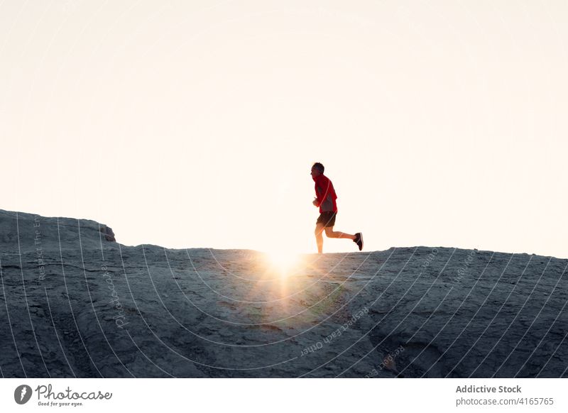 Anonyme Person, die bei Sonnenuntergang auf einem Hügel läuft laufen Berge u. Gebirge Berghang Training Athlet Aufstieg Silhouette Übung Gesundheit Sport
