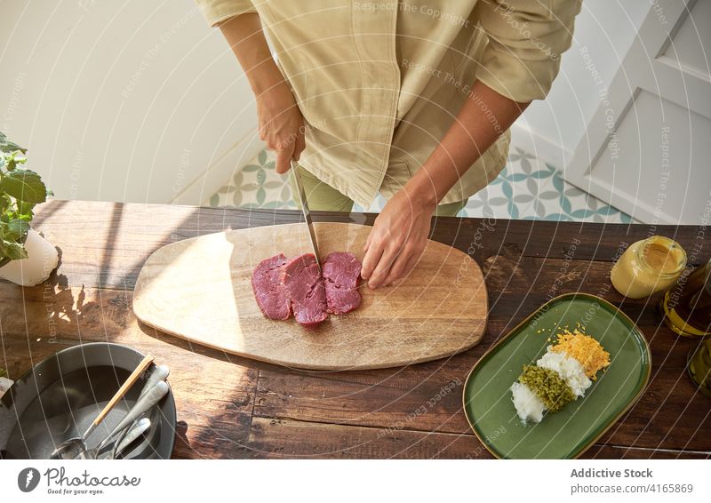 Crop Frau Schneiden von Fleisch in der Küche geschnitten Rindfleisch Koch Steak Tartar Hausfrau vorbereiten Abendessen Speise Schneidebrett frisch hölzern