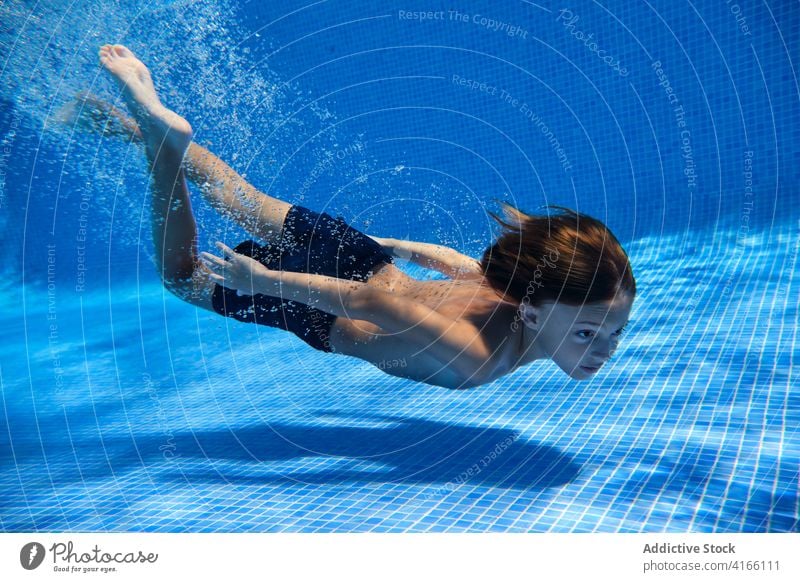 Teenager-Junge taucht ins Poolwasser Energie Sinkflug schwimmen aktiv unter Wasser Aktivität sorgenfrei spielerisch platschen aqua Resort Eintauchen genießen