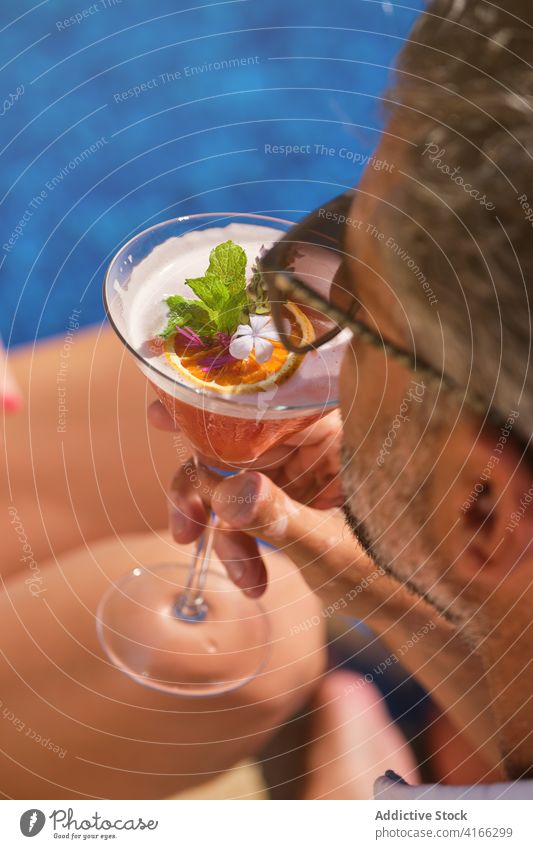 Crop Mann mit Glas tropischen Cocktail am Pool trinken Getränk Erfrischung Resort Feiertag Sommer exotisch sich[Akk] entspannen männlich Barkeeper sonnig