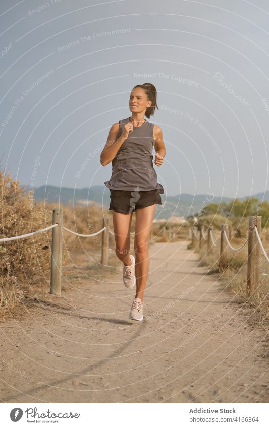 Starke Frau läuft auf dem Lande laufen sandig Küste stark Sportkleidung sportlich schnell joggen Ufer leer Strauch trocknen jung Übung Fitness Gesundheit Dame
