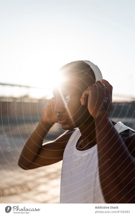Schwarzer sportlicher Mann beim Musikhören Läufer anonym benutzend Kopfhörer zuhören Training Athlet Pause Sportler Apparatur Sportbekleidung Drahtlos Lifestyle