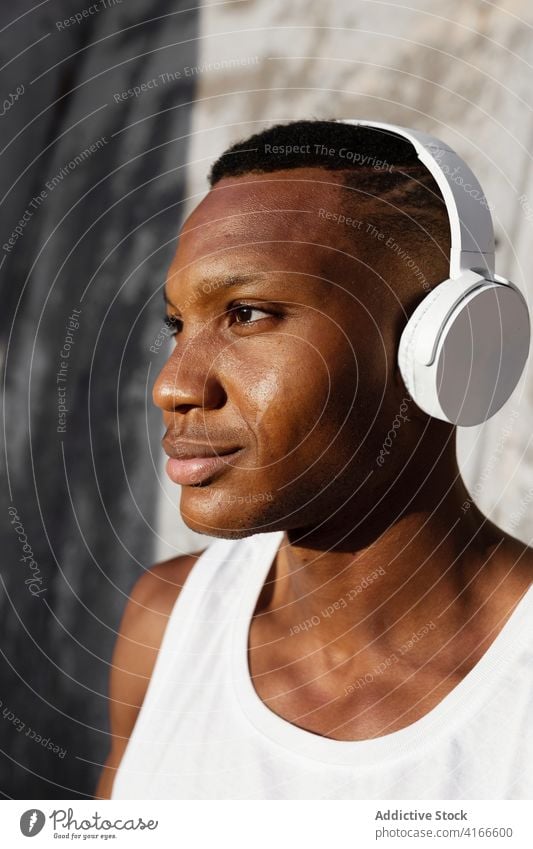Schwarzer ernster Mann, der mit Kopfhörern Musik hört sich[Akk] entspannen Gesang Athlet zuhören Drahtlos Klang männlich ruhen Audio Melodie Wellness