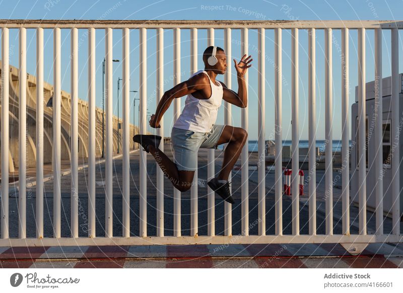Schwarzer Sportler, der beim Lauftraining hoch springt Mann Läufer über der Erde springen Energie Athlet physisch Training Ausdauer Sportlerin Kraft Gerät