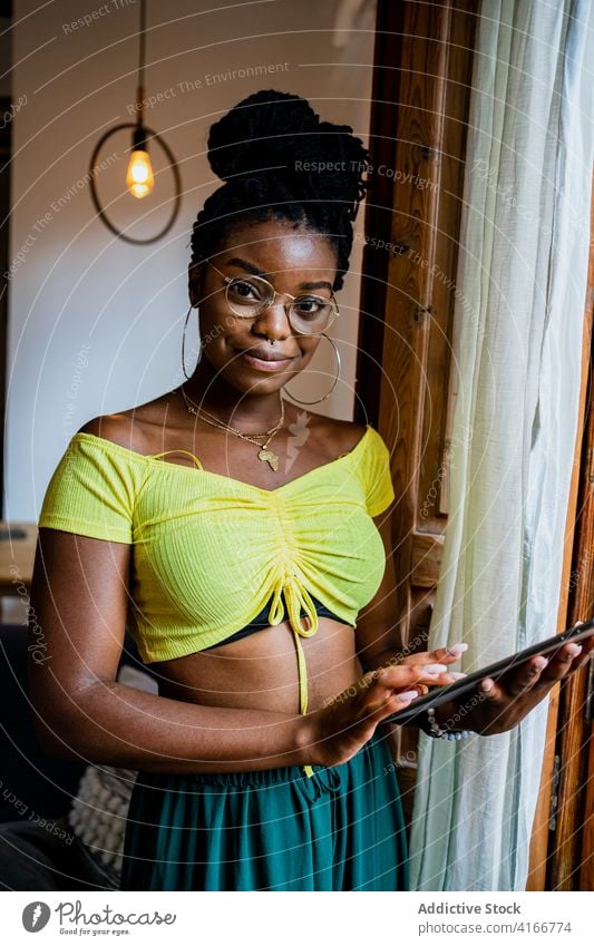 Positive junge Afroamerikanerin, die ein Tablet zu Hause benutzt Frau Browsen Tablette heimwärts abgelegen Job beschäftigt positiv Lächeln Apparatur Stil online