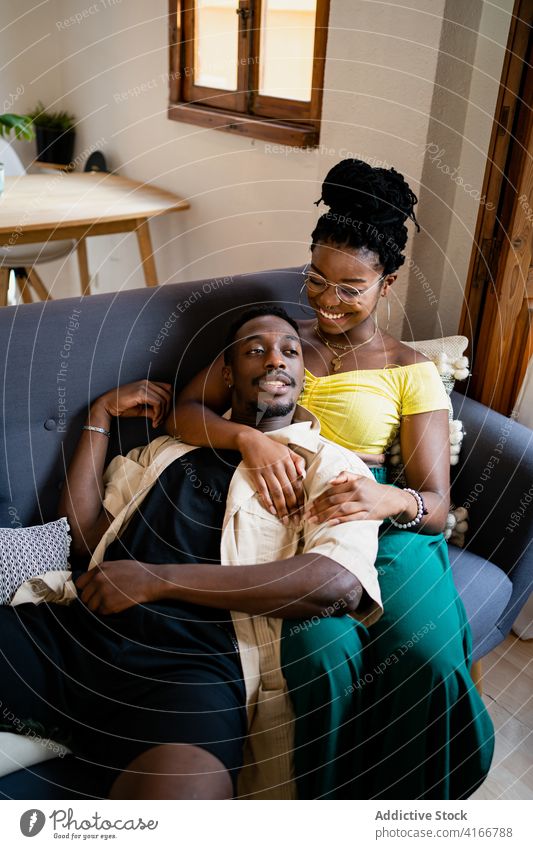 Glückliches schwarzes Paar verbringt Zeit zusammen in gemütlichem Zimmer Liebe Kälte romantisch Wohnzimmer Wochenende Bonden räkeln Lächeln Afroamerikaner