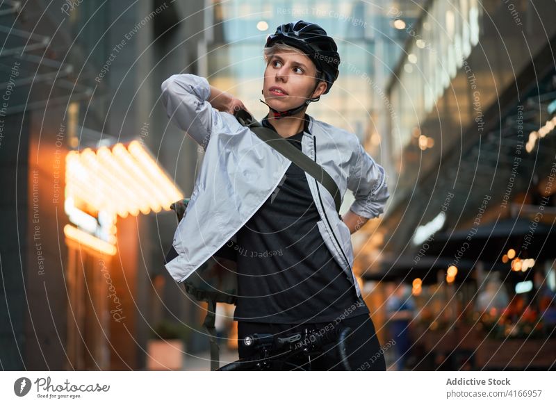 Nahaufnahme eines Mädchens mit Helm auf einem Fahrrad, das in der Nähe eines hohen Gebäudes zur Seite schaut Radfahrer gemauert Großstadt Tag Frau jung Sport