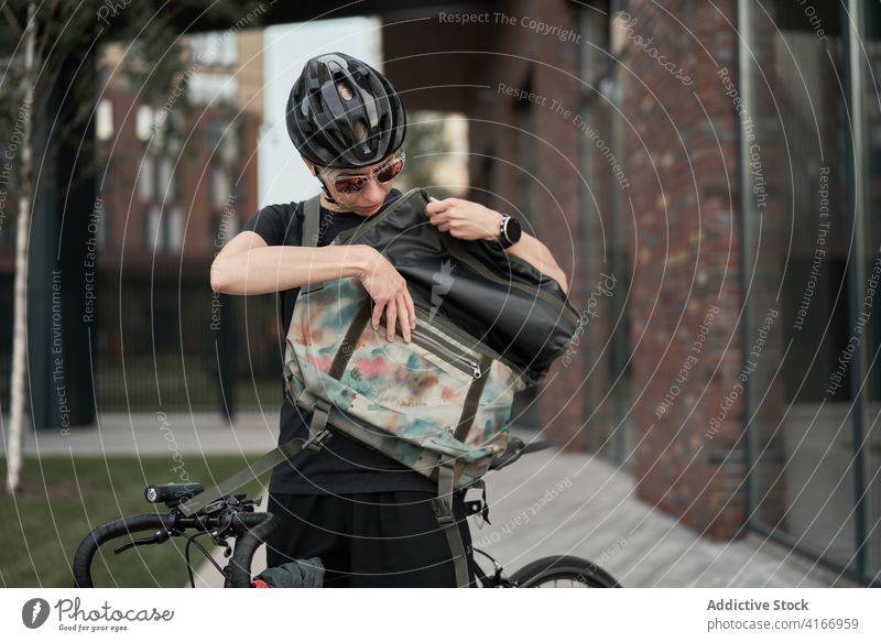 Weiblicher Kurier mit Tasche in den Händen auf der Straße Radfahrer Gebäude gemauert Großstadt Tag Frau jung Sport Reiten Sommer Schutzhelm schützend