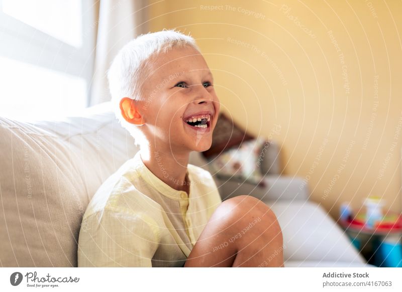 Positives Kind, das lächelt, während es sich zu Hause auf dem Sofa ausruht sich[Akk] entspannen Liege Lächeln heiter heimwärts Freizeit ruhen positiv bezaubernd