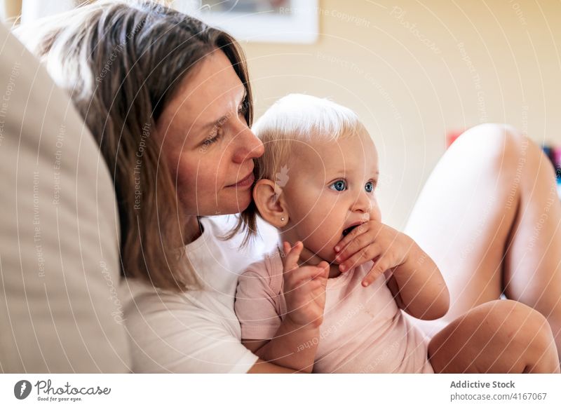 Ruhige Mutter, die ihre kleine Tochter auf dem Sofa umarmt Frau Umarmung Baby Liege heimwärts Glück Liebe Umarmen Augen geschlossen Bonden Pflege Erwachsener