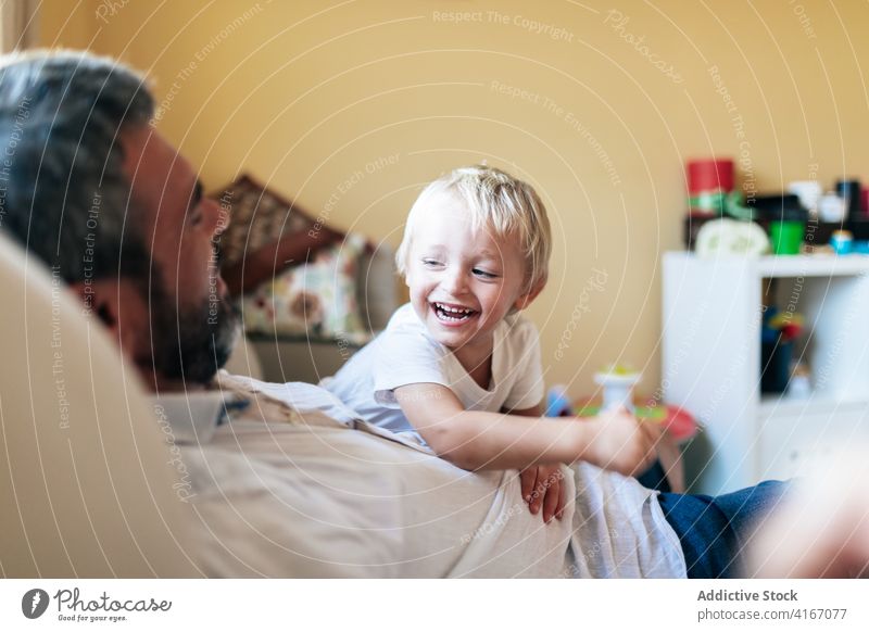 Vater spielt mit Sohn im Wohnzimmer Mann kuscheln heimwärts spielen Spaß haben heiter positiv Bonden unterhalten Kind Glück blond genießen Kindheit spielerisch