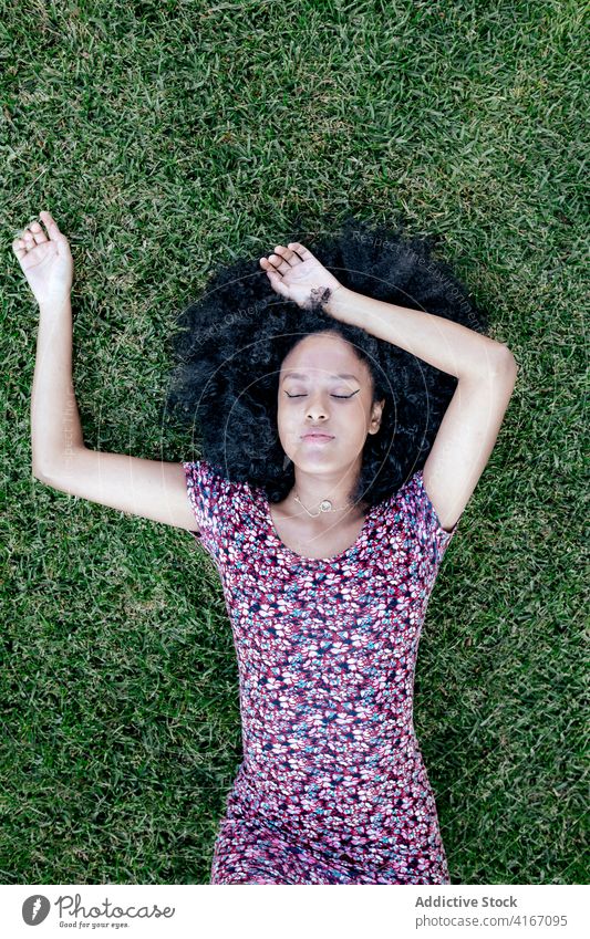 Müde Frau auf Gras im Park liegend Lügen schlafen sich[Akk] entspannen sorgenfrei verträumt Sommer genießen ethnisch schwarz Afroamerikaner Afro-Look Frisur
