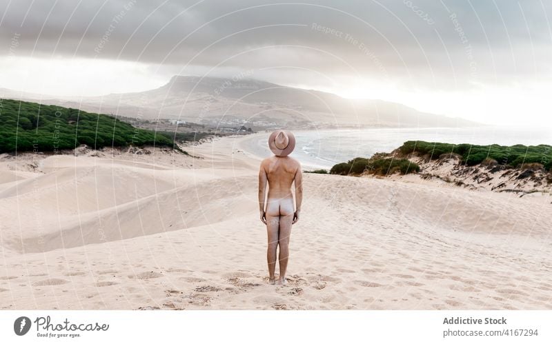 Anonymer sportlicher nackter Mann, der an der sandigen, trostlosen Meeresküste läuft laufen aktiv sorgenfrei Freiheit Strand malerisch reisen Meeresufer Hut