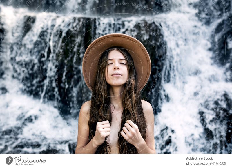 Ruhige nackte Frau in der Nähe von Wasserfall im Sommer frisch Air genießen Natur Deckung Brust ruhig Augen geschlossen sinnlich sich[Akk] entspannen