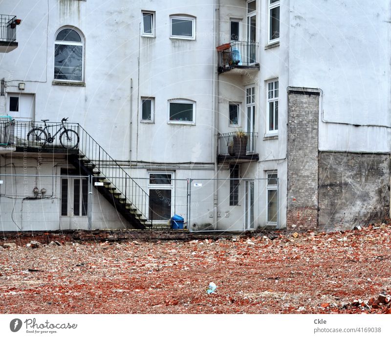 Schutt eines abgerissenen Hauses vor den Fenstern eines Altbaus Abriss Hinterhof Baustelle Zerstörung Fahrrad Ziegelsteine Balkone Treppe Aussicht Gebäude