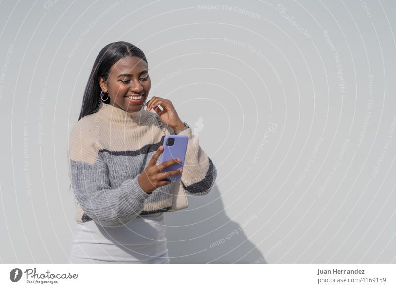Junge schwarze Frau mit einem lila Smartphone hübsch jung Afrikanisch Funktelefon Afro-Look Afroamerikaner junger Erwachsener Handy Nachricht Internet