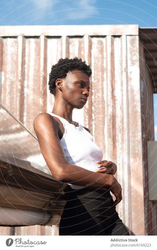 Entspanntes schwarzes weibliches Modell lehnt sich an eine Dachkonstruktion Frau verführerisch Dachterrasse Pose Verlockung Anmut Tastkopf feminin