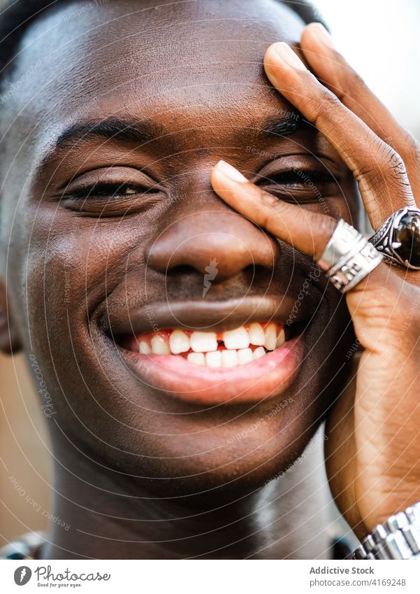 Fröhlicher schwarzer Mann schaut in die Kamera heiter Porträt gutaussehend Individualität Lächeln Vorschein jung tausendjährig Glück männlich ethnisch