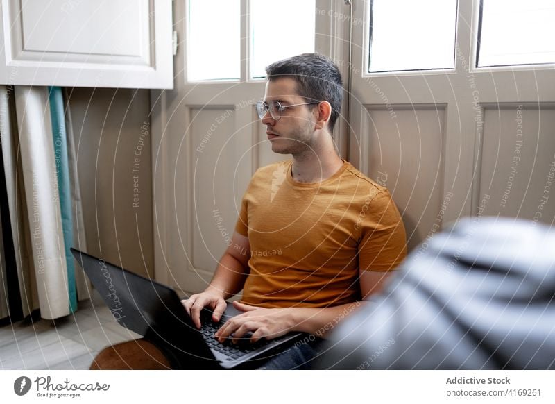 Beschäftigter Mann arbeitet am Laptop im Wohnzimmer freiberuflich abgelegen Arbeit heimwärts Tippen Projekt Konzentration Browsen männlich lässig Outfit Stock