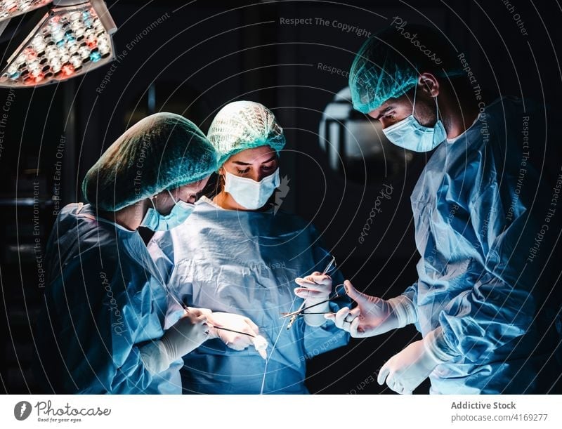 Ein Team von Medizinern bei einer Operation im Krankenhaus Chirurg Operationssaal Sanitäter Zusammensein Menschengruppe Faser Werkzeug Assistent sticken