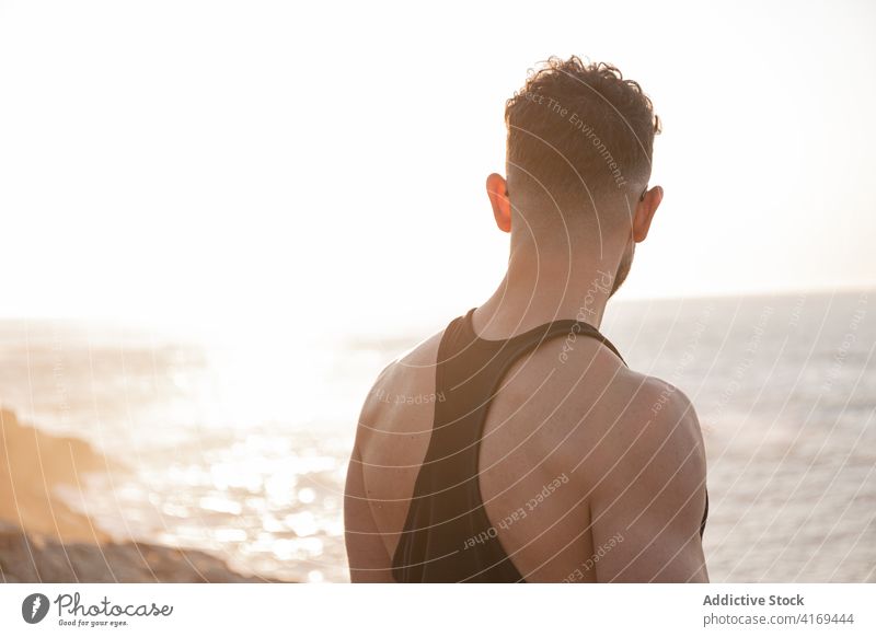 Ein muskulöser Mann strandet bei Sonnenuntergang am Meeresufer Athlet ruhig bewundern stark Sportler Sportbekleidung männlich Gesundheit Strand Training Sommer