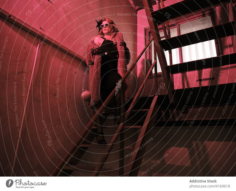 Stilvolle Dragqueen auf der Treppe stehend Mann Transgender elegant feminin androgyn Treppenhaus Rotlicht Outfit ausgefallen männlich Grunge Model Drag Queen
