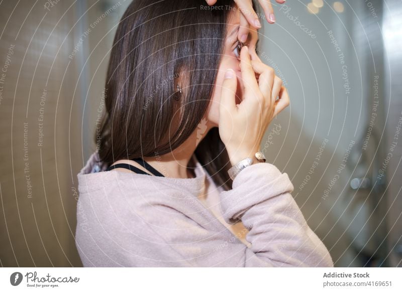 Frau setzt Kontaktlinse im Badezimmer auf Linse angezogen Auge Sehvermögen Augenlicht optisch Gesundheitswesen Routine heimwärts Pflege Ophthalmologie Blickfang