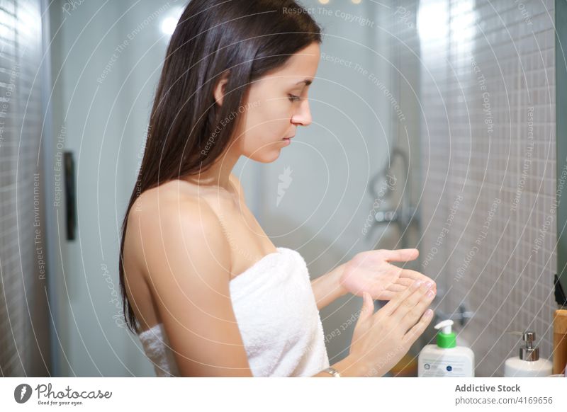 Gelassene Frau, die ihr Gesicht im Badezimmer eincremt Gesichtsbehandlung Sahne bewerben Hautpflege Schönheit Verfahren Leckerbissen perfekt ruhig Pflege