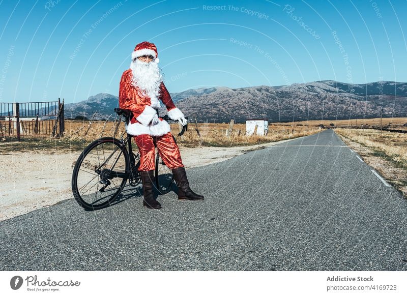 Weihnachtsmann in der Nähe von Fahrrad auf der Straße auf dem Lande Landschaft sich[Akk] entspannen Fahrbahn Fahrzeug Weihnachtsmütze männlich Vollbart Tracht