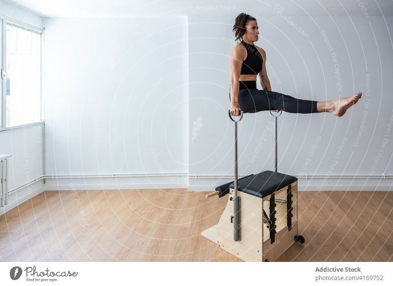 Konzentrierte Sportlerin bei Übungen auf dem Pilates-Stuhl Gleichgewicht Bauchmuskeln Unterleib üben Athlet Fitnessstudio Training Gesundheit Körper anstrengen