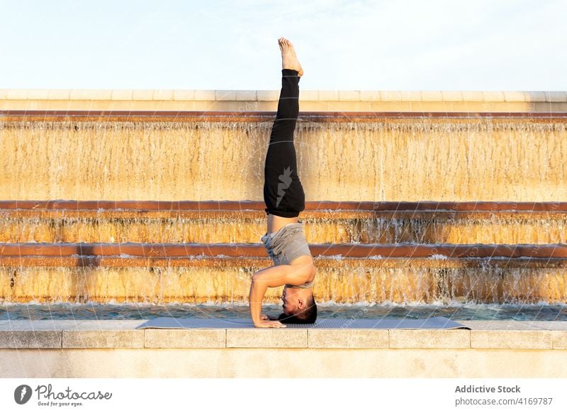 Mann im Kopfstand und beim Yoga Pose unterstützte Kopfstand-Pose Asana Gleichgewicht mental Zen meditieren männlich Unterlage Springbrunnen Großstadt Gesundheit