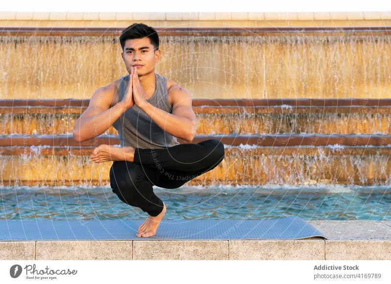 Flexibler Mann übt Yoga in Zehenstand-Pose Zehenspitzenstand-Pose Gleichgewicht beweglich Großstadt Stressabbau asiatisch Achtsamkeit mental ruhig ethnisch