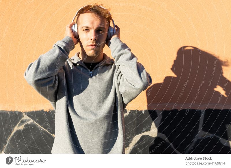 Junger Mann, der mit Kopfhörern Musik hört zuhören Drahtlos Hipster Sonnenlicht urban lässig Apparatur Gerät jung männlich modern Lifestyle Klang Audio Gesang