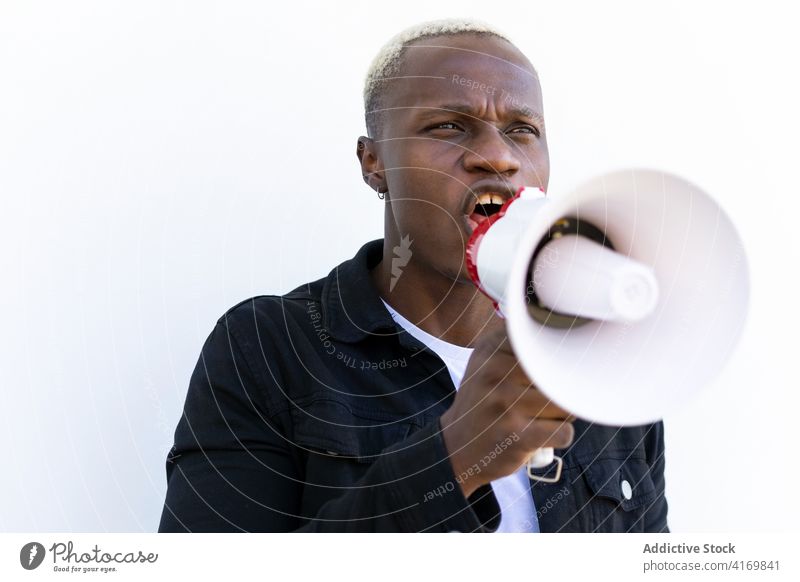 Aufgeregter schwarzer Mann mit Megaphon auf weißem Hintergrund Lautsprecher Schrei Hupe ankündigen verrückt aufgeregt heiter männlich ethnisch Afroamerikaner