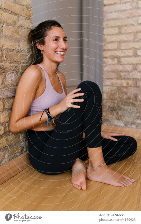 Junge Frau ruht sich im Yogastudio aus Pause Atelier Lächeln ruhen Lektion Backsteinwand Stock Sportbekleidung jung schlank passen Wellness Gesundheit Barfuß