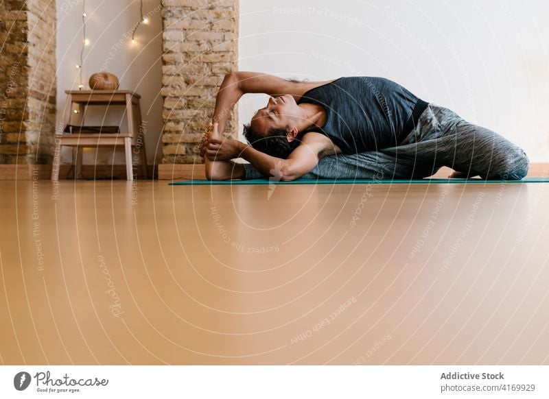 Mann streckt Körper in gedrehter Kopf-Knie-Pose Dehnung beweglich Yoga Atelier Drehung der Hecke zur Knieposition Wegbiegung Stock Lektion üben männlich